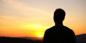 A person looking at a sunset in a calm landscape.